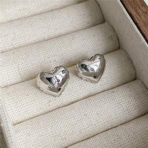 Boucles d'oreilles cœur en argent avec zircons colorés dans une boîte à bijoux beige