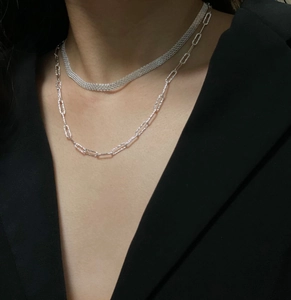 Detail of layered S925 sterling silver mesh and link chain necklace set on model