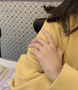 Three minimalist silver pearl rings worn on a hand, featuring an open adjustable design
