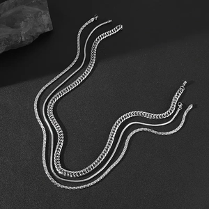 Ensemble de trois colliers argentés comprenant des mailles cubaines, serpent et tressées