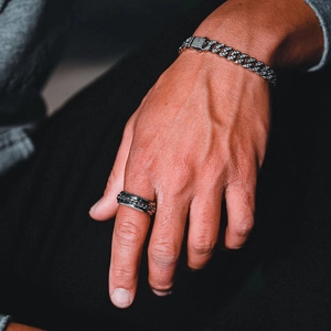Detail of silver Cuban chain bracelet with zircons and men's wide black chain ring