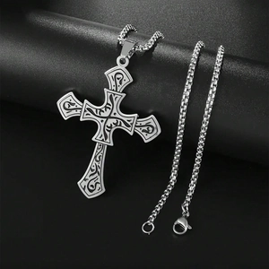 Macro shot of silver retro titanium steel cross pendant with intricate floral vine engraving