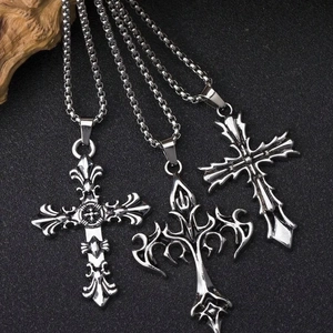 Vue détaillée de trois pendentifs croix gothiques vintage sur un fond de pierre sombre