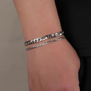 Detail of layered silver Figaro and thin link bracelets on wrist for a minimalist style