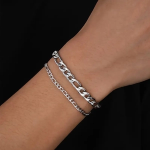 Detail of silver Figaro chain bracelet set for men on wrist showing metallic texture