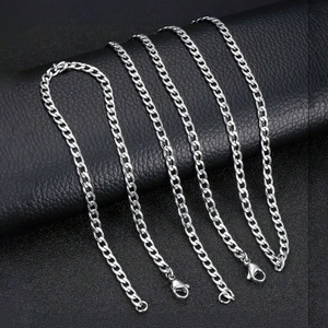Chunky silver stainless steel Cuban link chains with lobster clasps on black leather stand