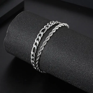 Detail of silver Figaro and rope chain bracelets set on a black cylindrical display stand