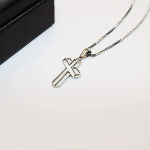 Three-dimensional hollow cross pendant necklace in silver stainless steel on white backdrop