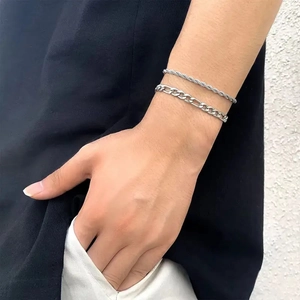 Detail of silver stainless steel rope and Figaro chain bracelets set on male wrist