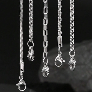 Dettaglio ravvicinato di cinque collane in acciaio inossidabile argento con varie maglie
