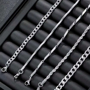 Detail view of five assorted silver metal chain bracelets displayed on a black tray