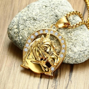 Gold horseshoe horse head pendant necklace with diamonds on rustic stone and wood