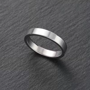 Detailed view of polished silver stainless steel band ring on grey stone texture