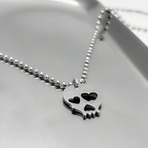Collier créatif argenté avec pendentif crâne aux yeux de cœur sur plateau métal