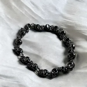 Macro detail of black punk skull link bracelet with lobster clasp on white silk fabric
