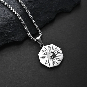 Collar con colgante Tai Chi Bagua vintage de acero inoxidable sobre fondo de roca negra