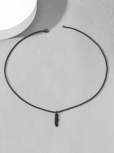 Macro detail of black feather pendant necklace with textured metallic finish and ring chain