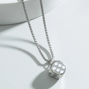 Macro shot of silver metal dice pendant with white dots and classic box chain