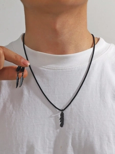 Close-up of black feather pendant necklace and matching earrings set on a model neck