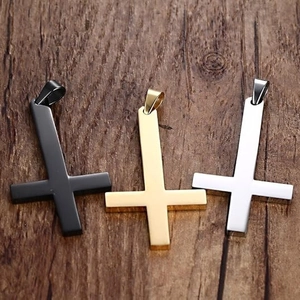Pendentifs croix pour hommes en acier noir, or et argent sur fond de bois sombre