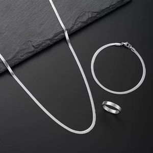 Flat silver snake chain necklace, bracelet and ring jewelry set on dark background