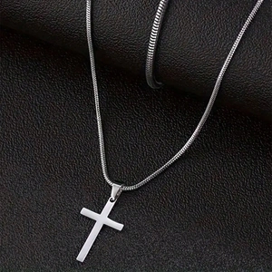 Pendentif croix en acier inoxydable avec chaîne serpent sur fond de cuir noir texturé