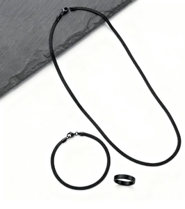 Flat lay of black stainless steel snake chain jewelry set with necklace bracelet and ring