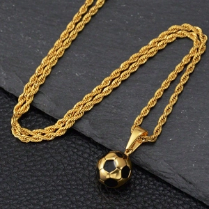 Gros plan du pendentif ballon de foot or et noir avec chaîne torsadée sur roche