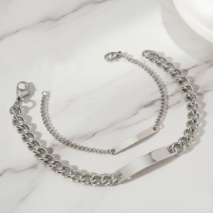 Matching silver stainless steel couples bracelets with engravable ID plates on marble background