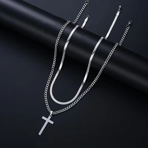 Detail of layered stainless steel Cuban chain and snake chain with cross pendant