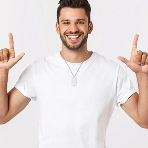 Close-up of a silver stainless steel dog tag necklace worn by a smiling male model