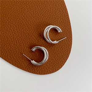 Macro detail of minimalist S925 sterling silver triple-layered hoop earrings