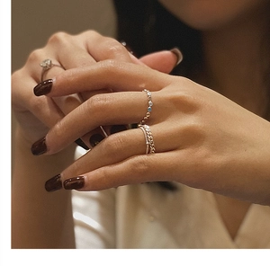 Close-up of stacked gold chain rings with sparkling zircon accents on woman's hand