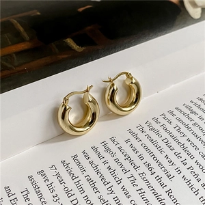 Polished S925 sterling silver chunky gold C-shaped hoop earrings on a vintage book