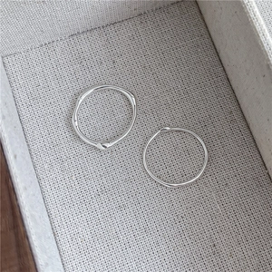 Close-up of S925 sterling silver rings with liquid lines and irregular texture on fabric