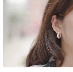 Close-up of minimalist polished silver thick C-shape hoop earrings on model