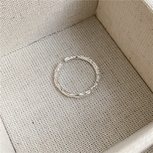 Minimalist S925 sterling silver ring with crumpled foil texture on a beige jewelry box