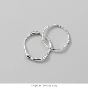 Detail of two S925 silver rings with irregular liquid texture and artistic wave patterns