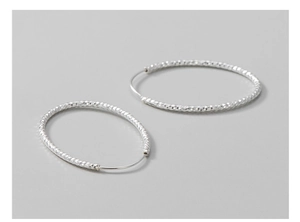 Detail view of large S925 sterling silver hoop earrings with diamond-cut texture finish
