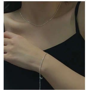 Detail of minimalist S925 sterling silver beaded chain necklace and bracelet on model