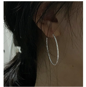 Macro shot of large S925 sterling silver hoop earrings with sparkling textured finish