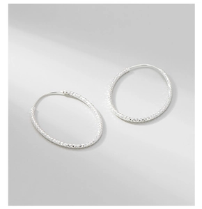 Macro detail of S925 sterling silver hoop earrings with diamond-cut sparkling texture