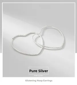 Close-up of sparkling heart hoop earrings in pure S925 sterling silver with faceted texture