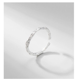 Macro shot of silver ring with irregular hammered texture and modern crushed foil finish