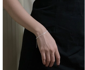 Detail of elegant triple-layered S925 silver bracelet worn on wrist against a dark backdrop