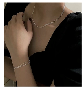 Close-up of minimalist layered S925 silver chain bracelet and necklace on model neck