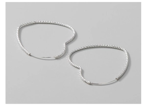 Macro detail of S925 sterling silver stamp on shimmering heart-shaped hoop earrings