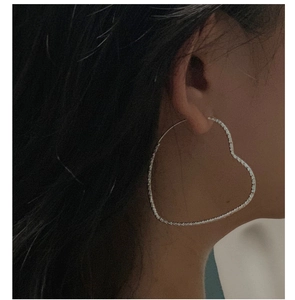 Detailed view of large heart-shaped S925 silver earrings with shimmering textured surface