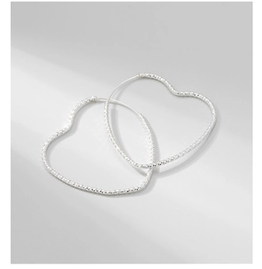 Macro detail of silver S925 heart hoop earrings with diamond-cut sparkling texture