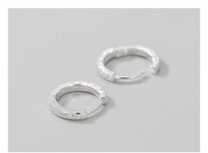 Detail shot of shimmering stardust texture on silver hoop earrings with a sleek finish